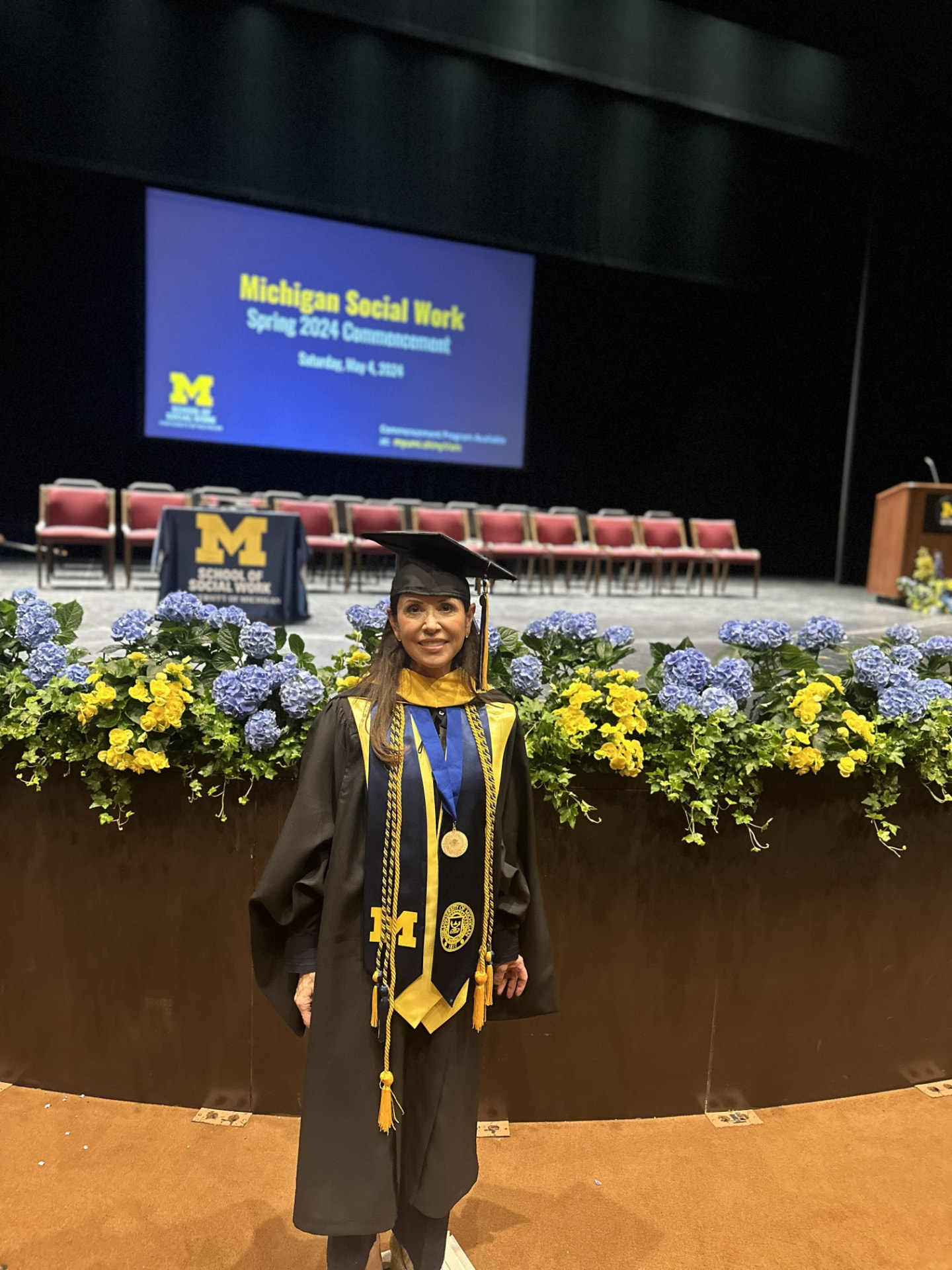 Lisa Neilson in front of the Michigan Social Work Spring 2024 Commencement stage